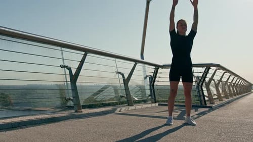 Fitness young sportswoman girl in the morning doing warm-up exercises before training on the street