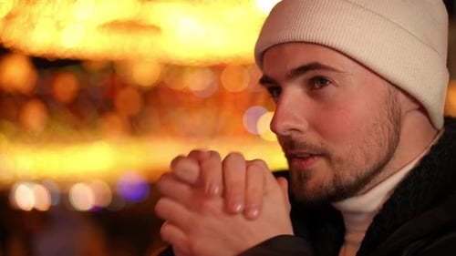 Closeup Side View Young Caucasian Man Blowing on Palms Warming Hands Standing at Background of New