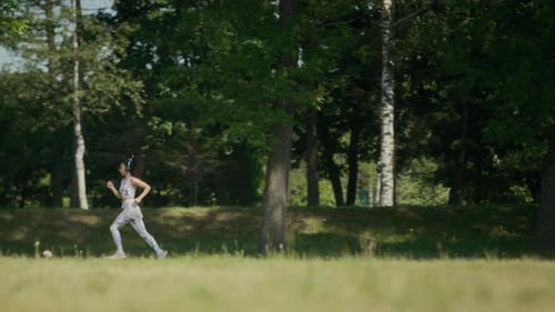 Young Woman in Headphones Running in Park