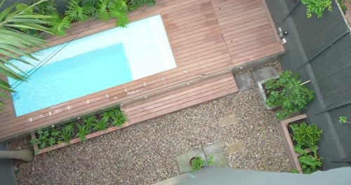 Camera is rotating clockwise and panning over plunge pool with deck revealing palm fronds and table