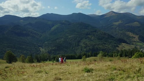 Family hiking through green hills enjoying summer vacation day mountain view