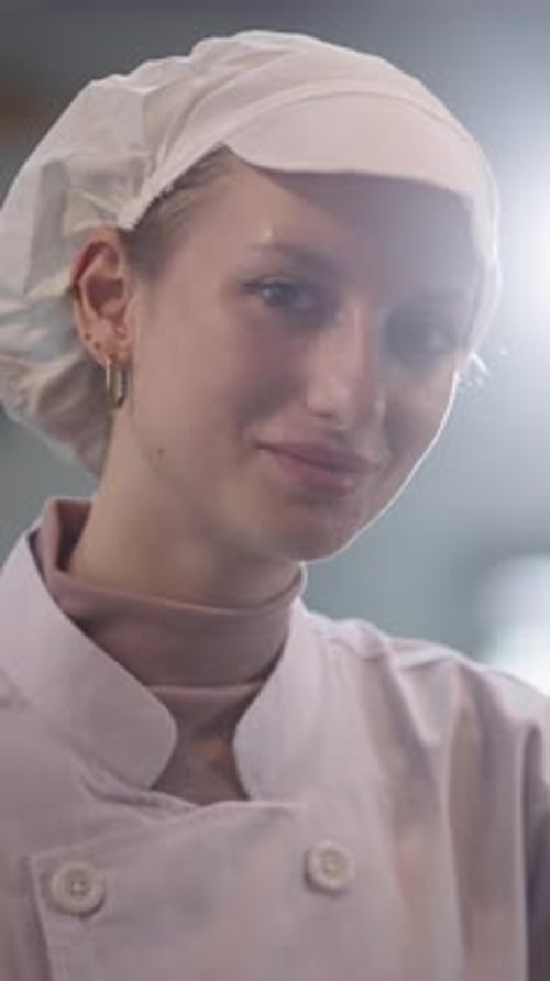 Smiling woman chef focuses on food preparation in restaurant kitchen