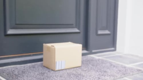 Delivery in cardboard box on ground outside front door, slow motion