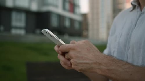 Man Using Cellphone in Urban Setting During Daytime