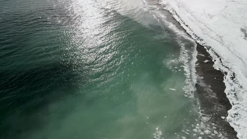 une vue aérienne de quelques vagues qui s'écrasent sur la plage en hiver