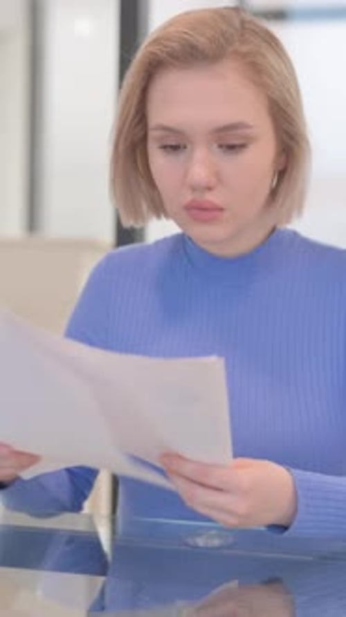 Young Woman Reviews Paperwork in Modern Office
