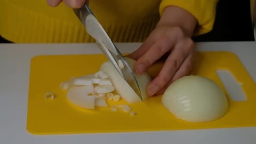 Slicing White Onion with Sharp Knife on Board