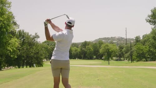 Male golfer hits wedge shot on par 3 golf course during middle of sunny summer day, golf swing in 4k