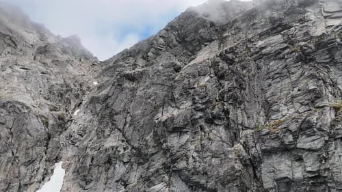 Un rocher alpin s'élève sur une pente accidentée et accidentée dans les nuages