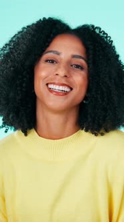 Visage, drôle et femme en studio, sourire et énergie positive sur fond bleu
