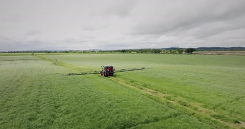 tractor operating a continuous spray on a farm rotating aerial shot