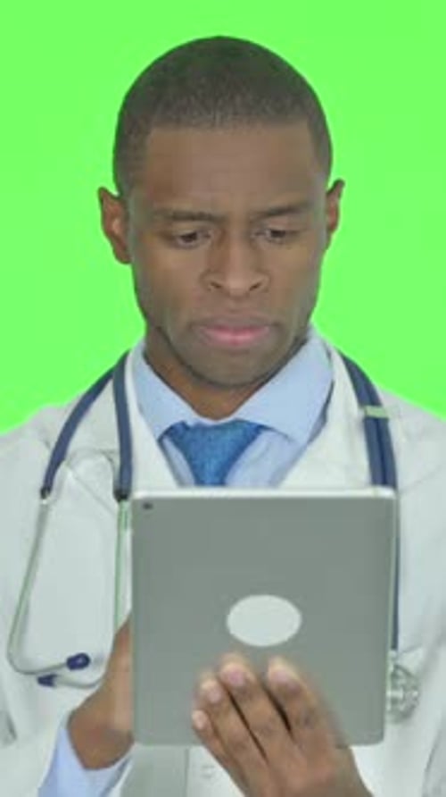 African Doctor using Digital Tablet on Green Background, Vertical Video