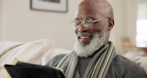 Senior Man Laughing at Tablet Indoors