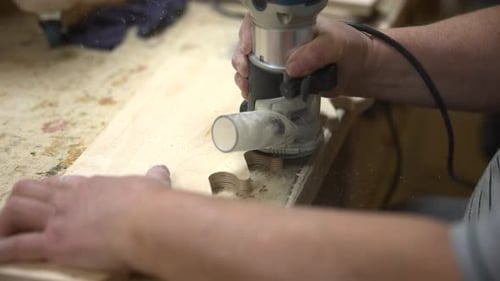 Man Using Router Tool on Wood in Workshop