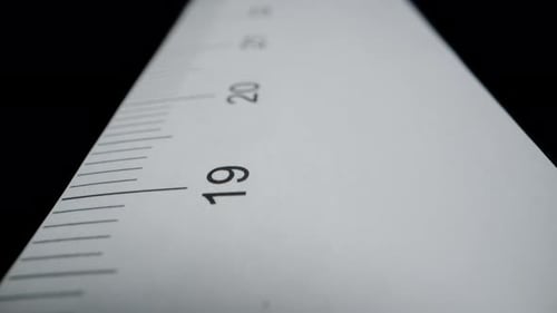 Paper ruler on a black background, with centimeter measurements. Dolly slider extreme close-up.