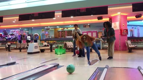 Frau, die mit Freunden einen Strike in Zeitlupe bowlt