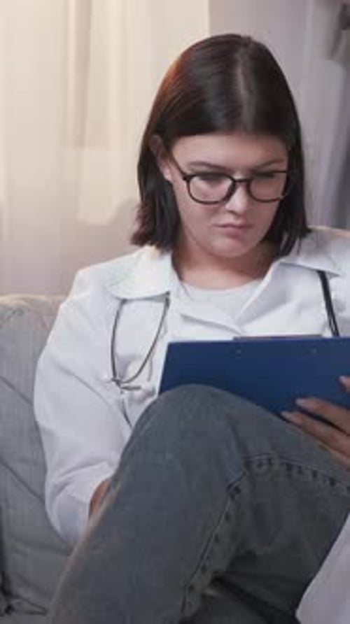 Woman Doctor Writing on Clipboard at Home