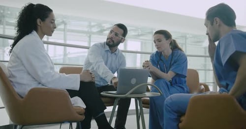 Medical Professionals Collaborate around Laptop in Modern Setting