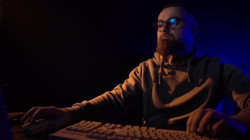 Man Working on Computer in Dark Lit Room