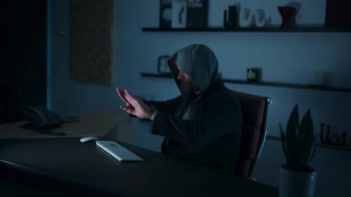 Hooded hacker man sliding an invisible manipulatable hologram
