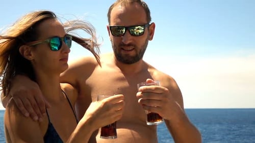 Couple raising a toast with drinks on a sailboat at sea in super slow motion