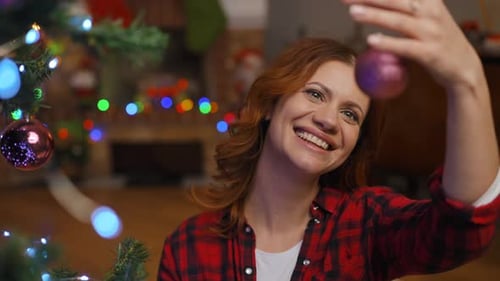 Woman Decorating Christmas Tree with Shiny Ornaments