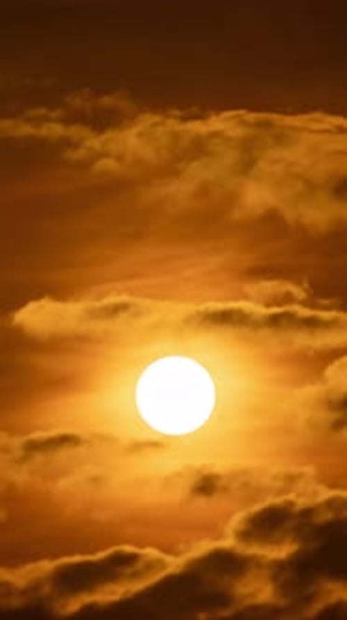 Ciel peint dans des tons de lever de soleil, le soleil projetant une lueur chaude à travers des nuages duveteux