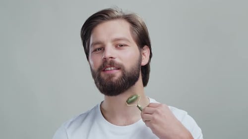 Studio Portrait Attractive Bearded Male Applying Beauty Tool Massaging Jade Roller Stone Face for