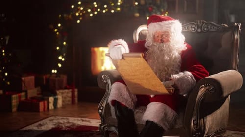 Santa Claus Reading Scroll by Fireplace at Christmas