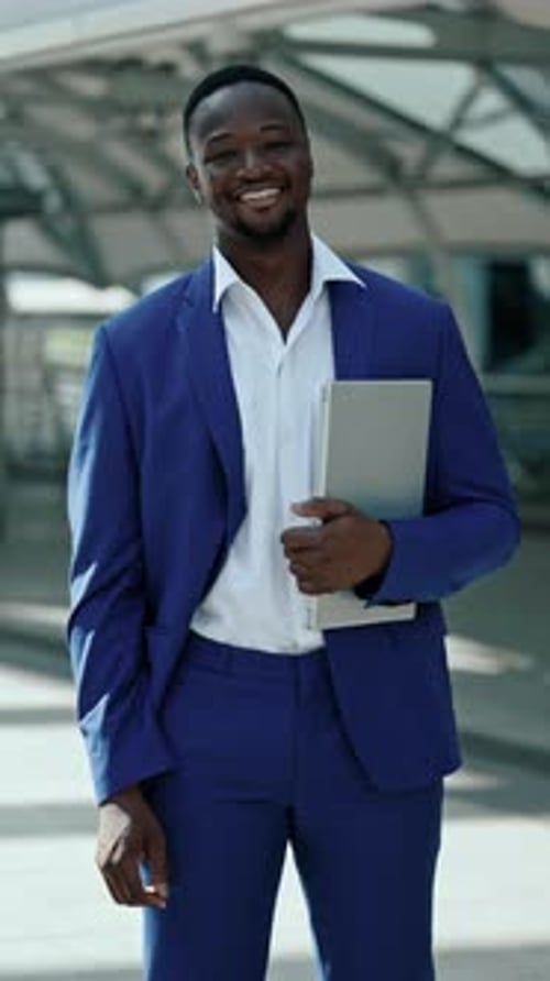 Portrait of African American Manager Holds Laptop Standing Near Business Center