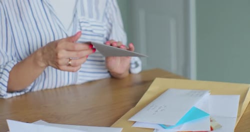 Woman Reading Cards and Letters at Wooden Table
