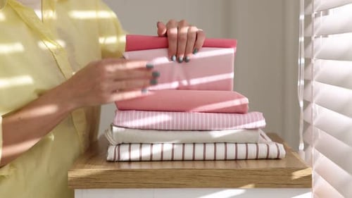 Woman with stack of clothes indoors, closeup
