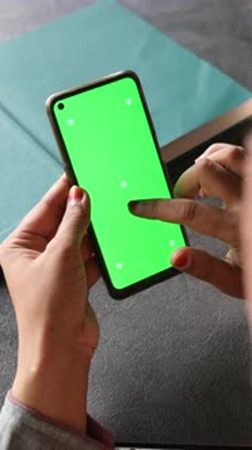 A Person is Using a Smartphone with a Green Screen for a Mockup in an Office Setting