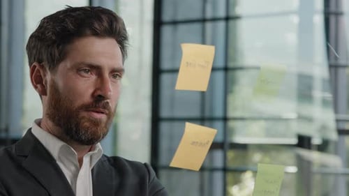 Man Reviews Notes on Glass Wall in Office