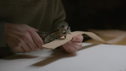 Tanneur utilisant une perforatrice rotative sur un bracelet en cuir