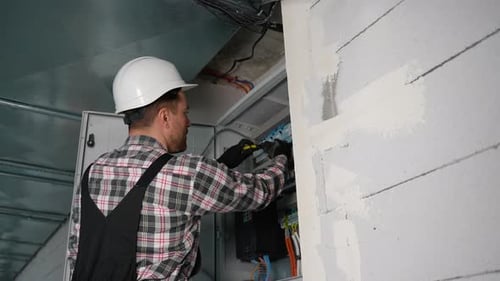 Electrician Working on Electrical Panel Installing Cables