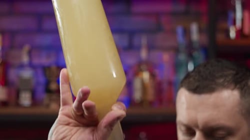 Vídeo a cámara lenta del camarero vertiendo alcohol de una botella en una taza medidora