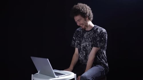 The psychotic schizophrenic laughs at what he sees on the laptop.