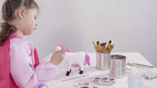 Kleines Mädchen malt Pappmaché-Figuren mit Acrylfarbe für ihr Homeschooling-Kunstprojekt