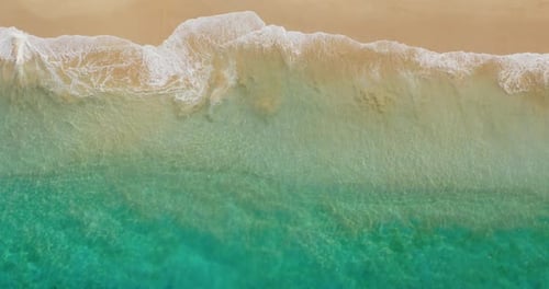 Aerial view of turquoise ocean wave reaching the coastline. Beautiful tropical beach