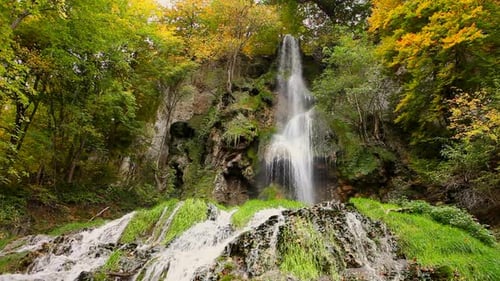 Breathtaking High Waterfall Cascading Down Mossy Cliffs in Autumn Forest