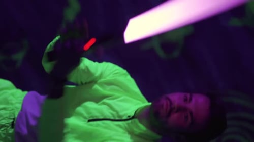 Young Guy are Having Fun in a Neon Park Man Fighting and Practicing Using Light Saber Vertical Video