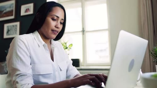 Woman in white shirt types on laptop computer