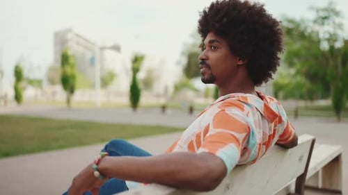 man sitting relaxed on park bench looking away