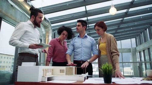 Group of Young Architects with Model of a House Standing in Office,