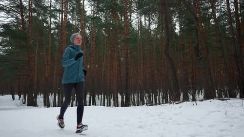 Woman Runs Through Snow in Winter Forest