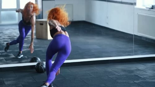 Sporty redhead girl with muscular body type doing exercises for legs by running
