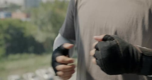 Closeup of Wrapped Hands of Male Boxer Hitting Fists Preparing for Fight in Modern Gym