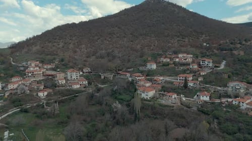Drone zoom out FLIGHT above a village on a high hill in, red roof tops, little houses, SCENIC mounta