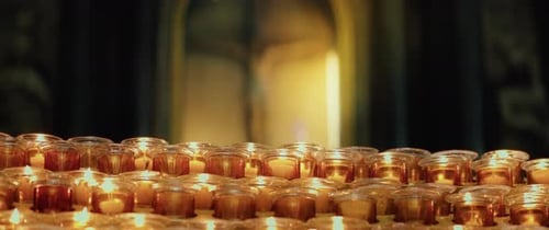 Burning candles in the church. Orthodox cross with crucifixion of Jesus Christ. Christian faith in G